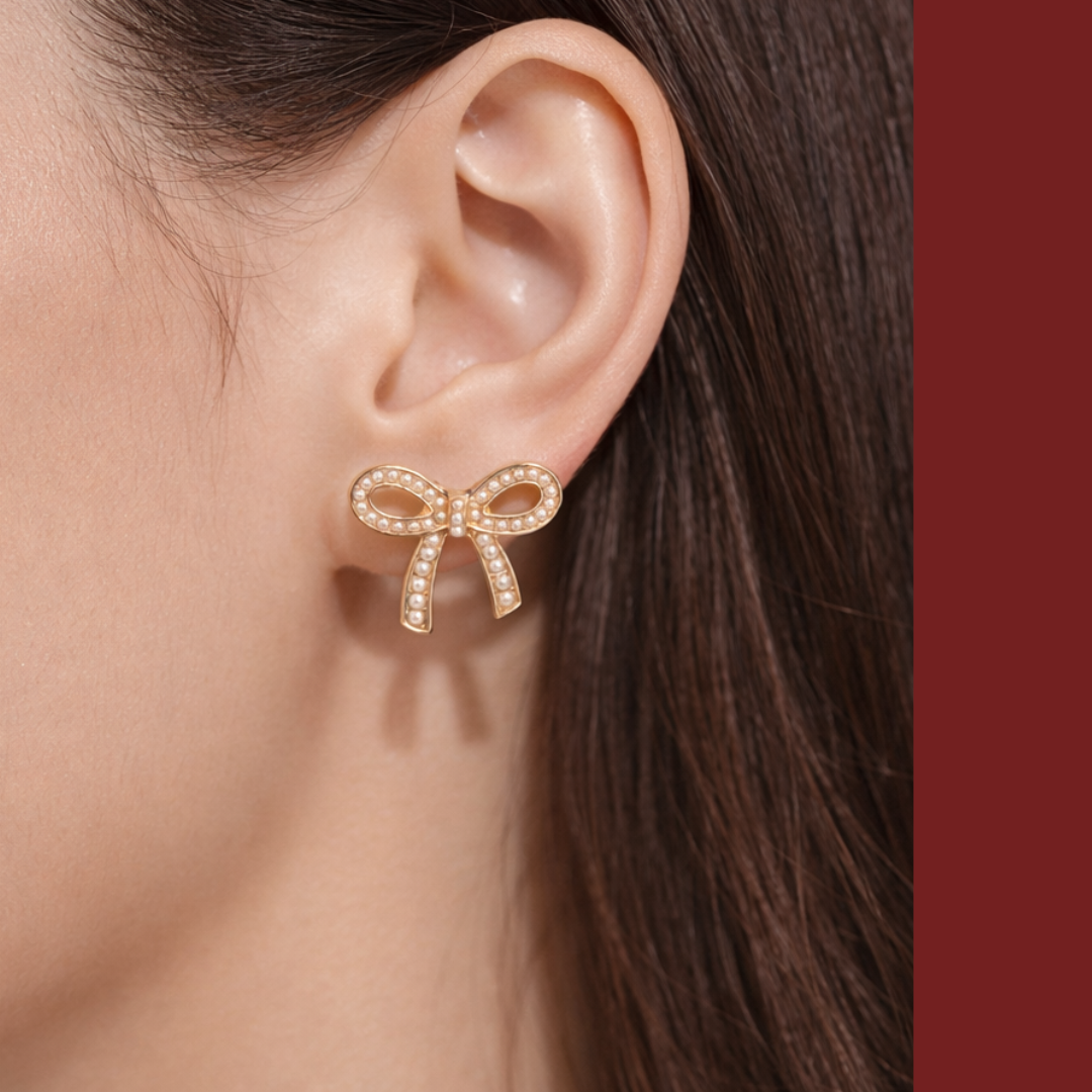 Woman wearing elegant gold bow stud earrings with pearl accents.