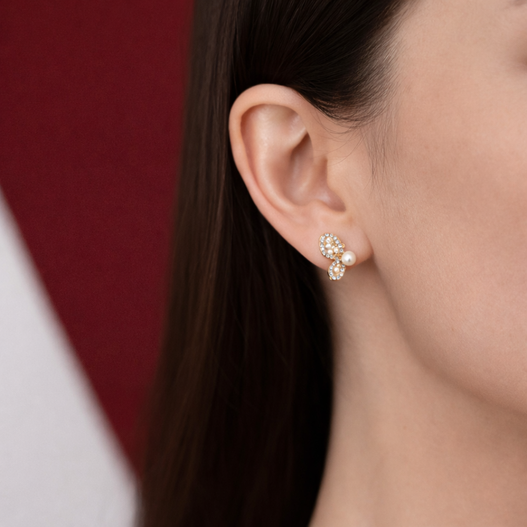 Close-up of butterfly stud earrings with pearl on woman