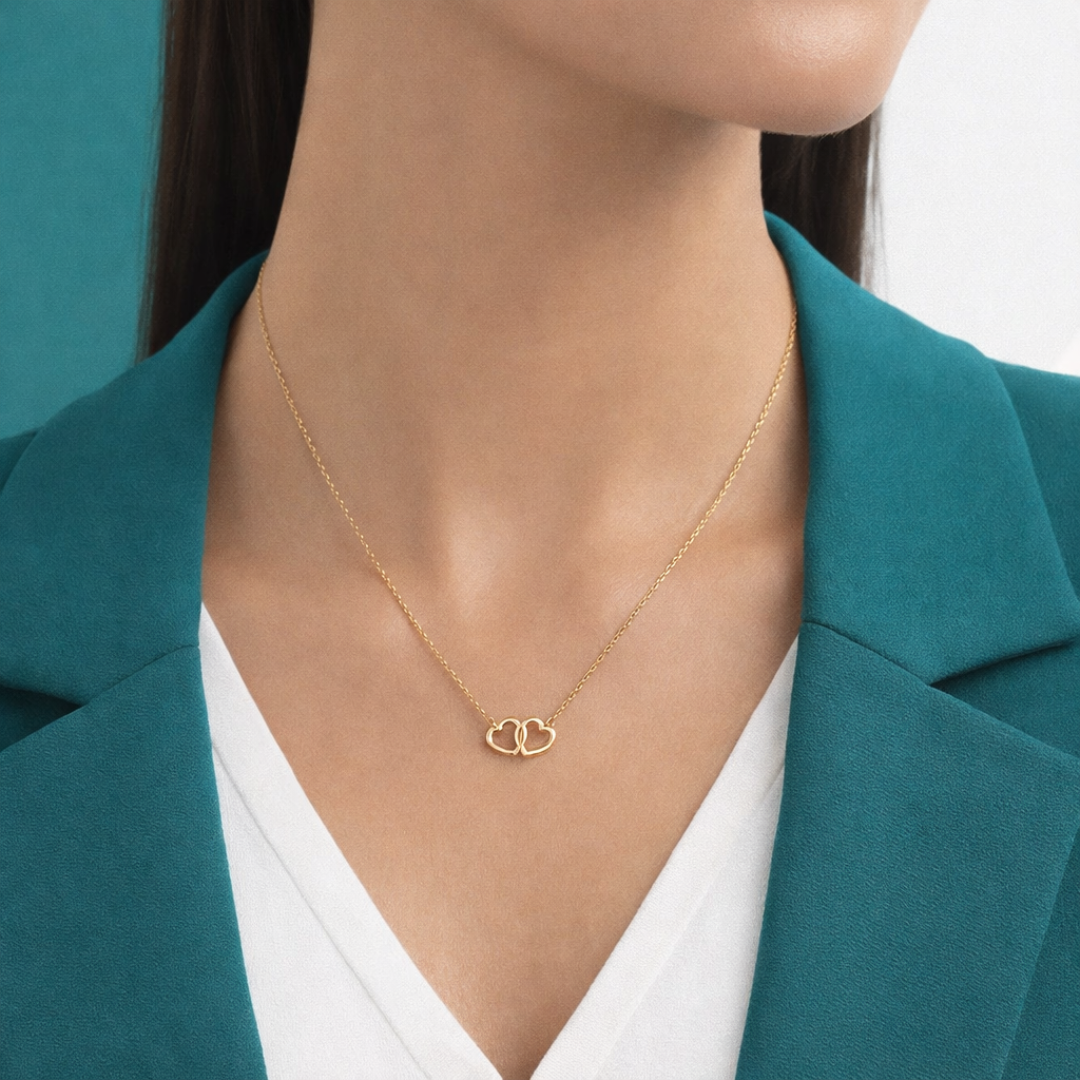 Delicate gold double heart necklace on woman’s neck with minimalist design